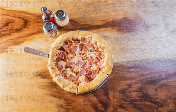 Ham pizza with cheese edge on wooden background. Top view of ham and cheese pizza on wooden table