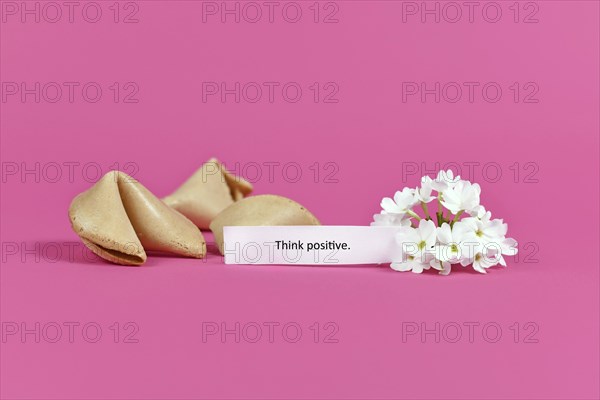 Positive thinking concept with fortune cookies with motivational text saying Think positive on pink