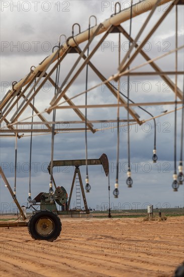 Plains, Texas, An oil well near irrigation equipment on farm land in the Permian Basin