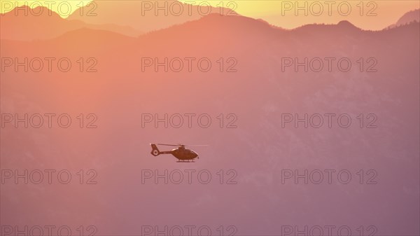Rescue helicopter Christoph in flight in the evening over the Berchtesgaden Alps, Bavaria, Germany,