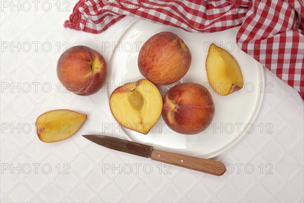 Cut peaches with knife on plate (Prunus persica)