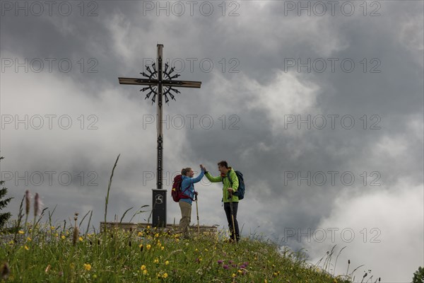 Young couple climbing, hiking, summit cross Brauneck, bad weather, fog. Brauneck near Lenggries,