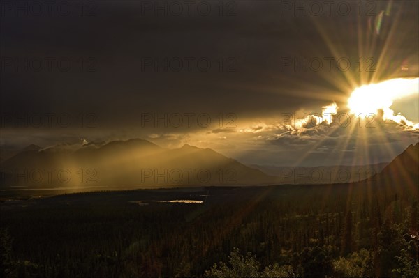 Sun in the evening breaks through the dense cloud cover in the subarctic tundra landscape, Denali