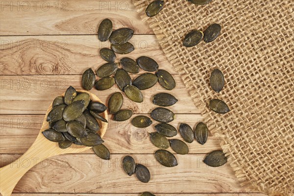 Dark roasted pumpkin seeds without husks on wooden table