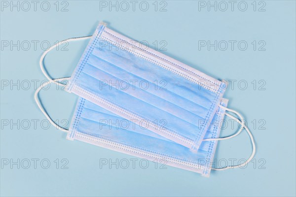 Two disposable medical face masks on blue background