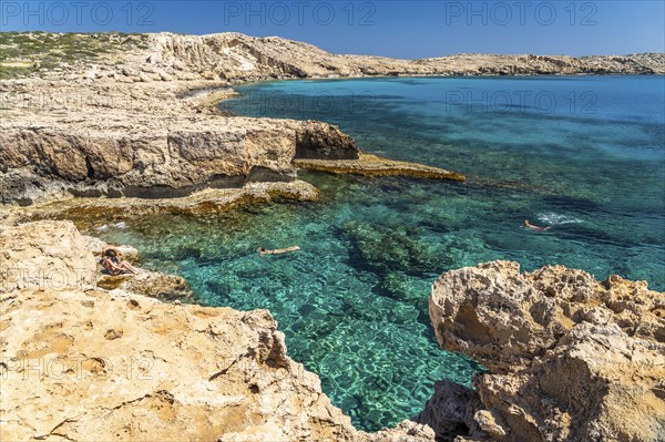 Tourists bathing in the crystal-clear turquoise waters of the Cape Greco peninsula, Agia Napa,