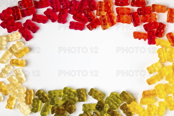 Frame made of gummy bears in assorted colours, from above, white background, copying space in the
