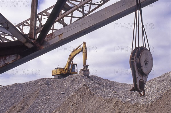 Excvator on top of shingle pile at gold dredge, Westland, New Zealand, Oceania