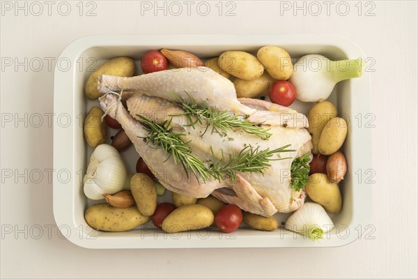 Roast chicken prepared for roasting with young garlic, shallots, parsley, cherry tomatoes, potatoes