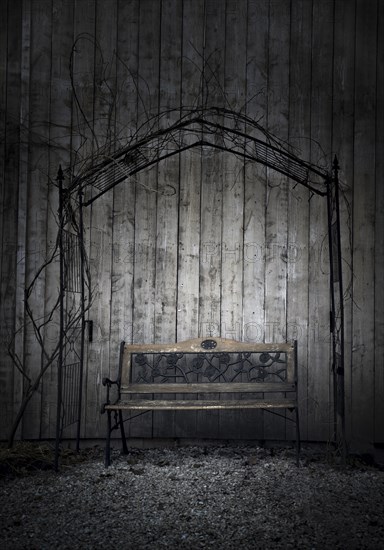 Retro garden bench near a wooden barn, in a cold day of january, under a metal arch