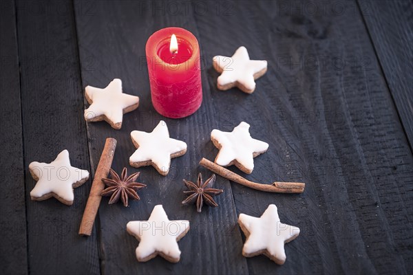 Homemade cinnamon and nuts cookies, star shaped, with decorative spices between them, on an old