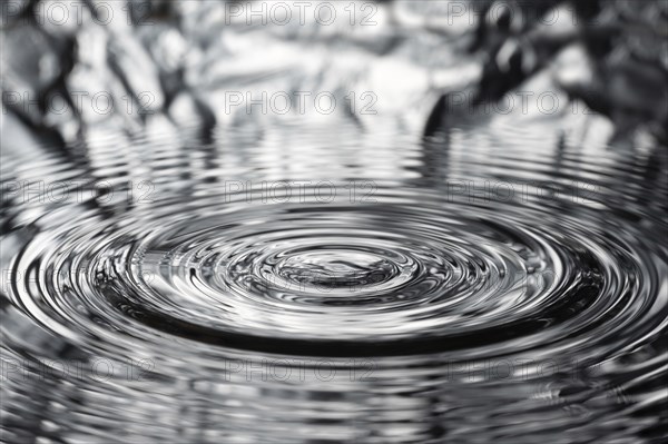 A drop of water causes concentric waves, circles and rings on the surface of the water