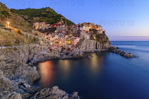 Sunset and night view of Manarola, one of the five Mediterranean villages in Cinque Terre, Italy,