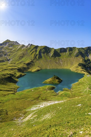 Schrecksee in the midst of green mountains under a clear sky, surrounded by lush vegetation and a