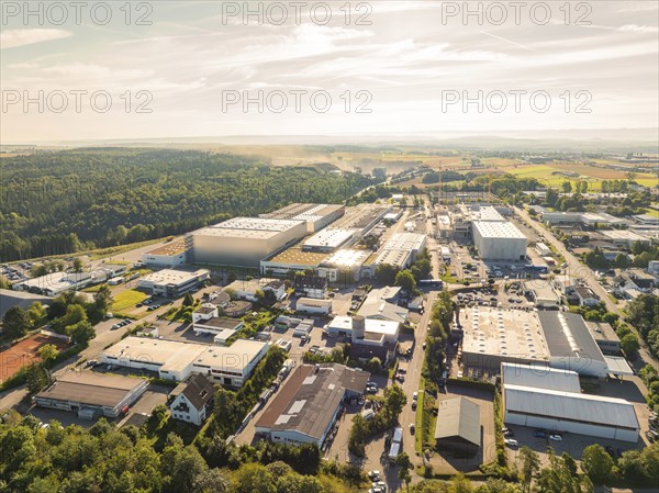 Industrial area with numerous buildings, streets and trees in a scenic setting under a clear sky,