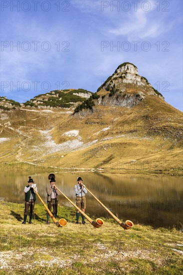 Three men play the alphorn at Lake Augstsee on Mount Loser. The Austrian alphorn trio Klangholz.
