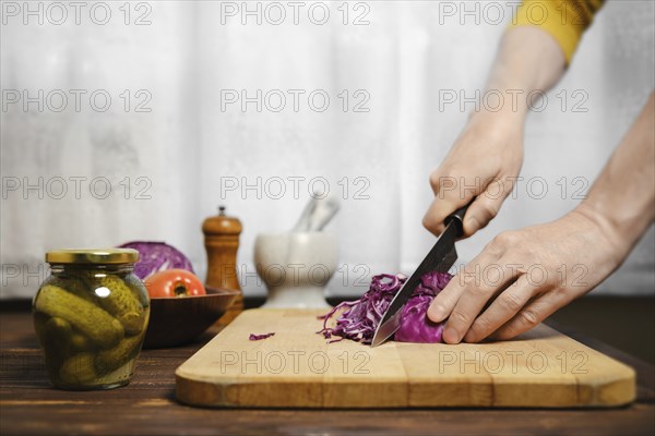Unrecognizable man cutting red cabbage in the kitchen