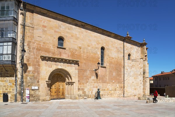 A simple historic church with a sandstone-coloured façade and large doors in an empty square under