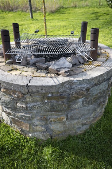 Outdoor barbecue, barbecue from an old well, two used grill grates lying on top, four metal pipes