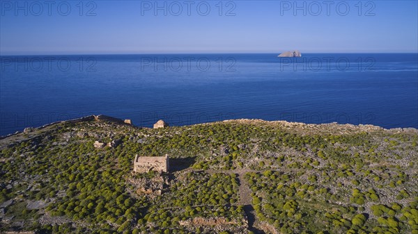 Drone shot, ruins on cliffs by the sea with sweeping views and lush vegetation to the horizon,