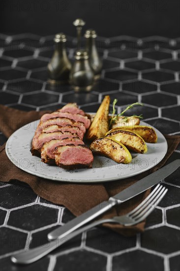 A succulent duck breast is perfectly seared and surrounded by tender, caramelized apple and pear