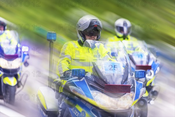 Police on motorbikes in bright safety clothing in motion with a blur effect on a street, Stuttgart,