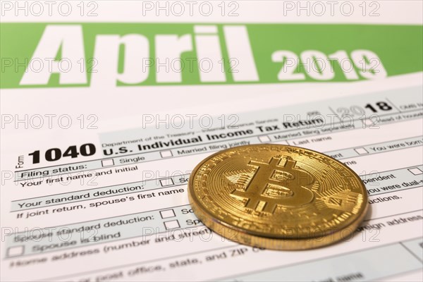 Bitcoin with 1040 income tax form for 2018 showing tax day for filing on April 15