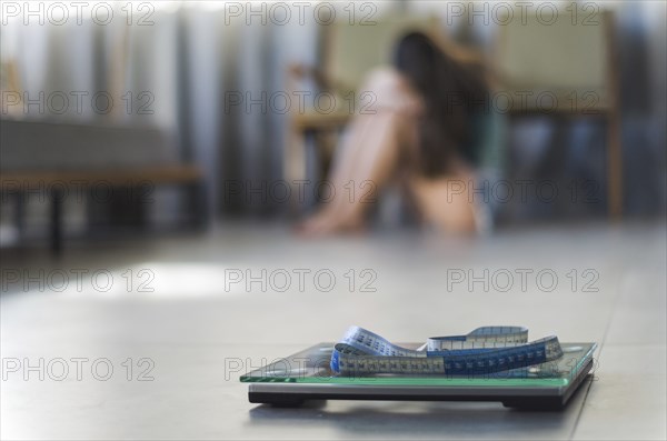 Concept of failing in weight loss, scales in the foreground and frustrated frustrated woman in the