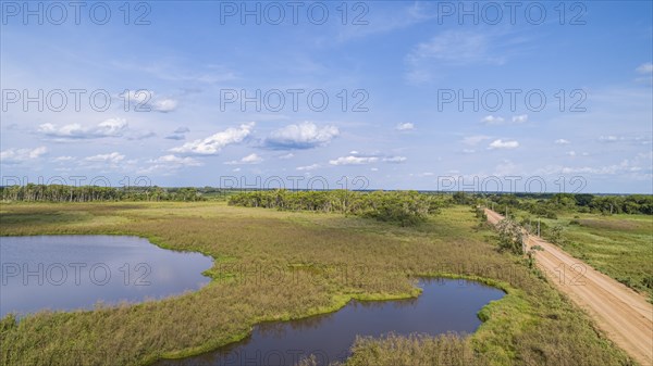 Aerial view of Transpantaneira dirt road along a typical lagoon and meadow landscape, with blue