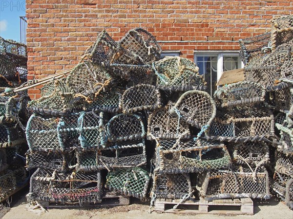 Lobster pots used in traditional fishing for crustaceans stacked against a building in scarborough