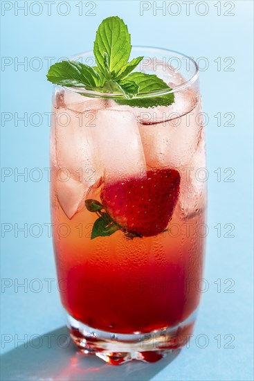 Glass of strawberry drink with ice cubes and mint leaves on a seamless blue background. A single
