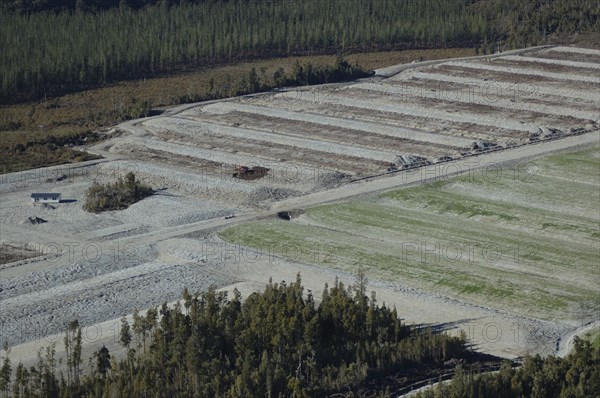 Digger excavating land to make humps and hollows for farmland, West Coast, South Island, New