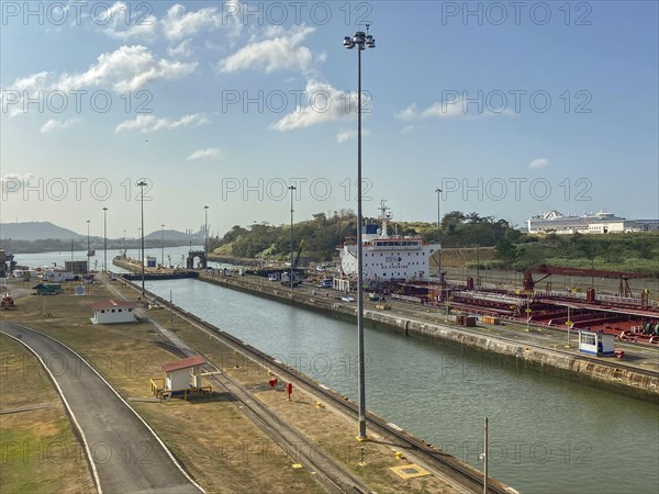 A ship moves through a canal surrounded by streets and lampposts. The atmosphere is calm and the
