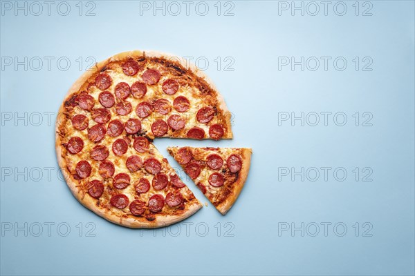 Pepperoni pizza on a blue background top view. Traditional italian food. Flatlay with a home-baked