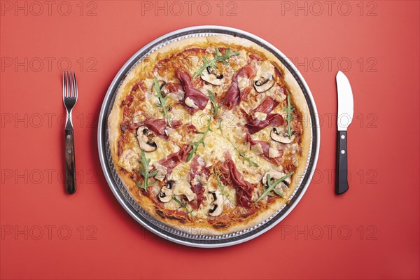 Homemade pizza with prosciutto crudo, arugula, mozzarella and champignons. Flat lay with a ham