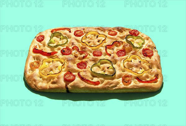 Homemade focaccia with vegetables and sourdough, in bright light minimalist on a green table.