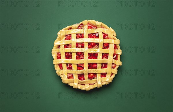 Strawberries and rhubarb pie with a lattice crust, above view on a green background. Top view with