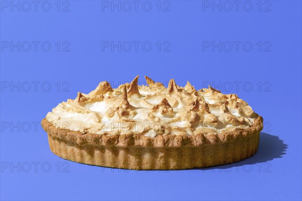 Delicious homemade meringue cake with a lemon flavor filling, minimalist on a blue indigo table.