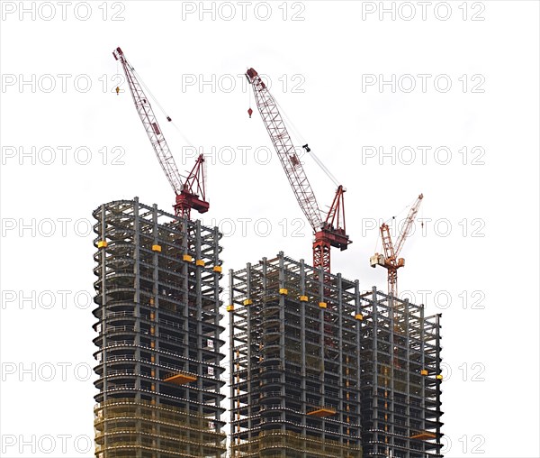 Half finished skyscraper steel frames with cranes on top