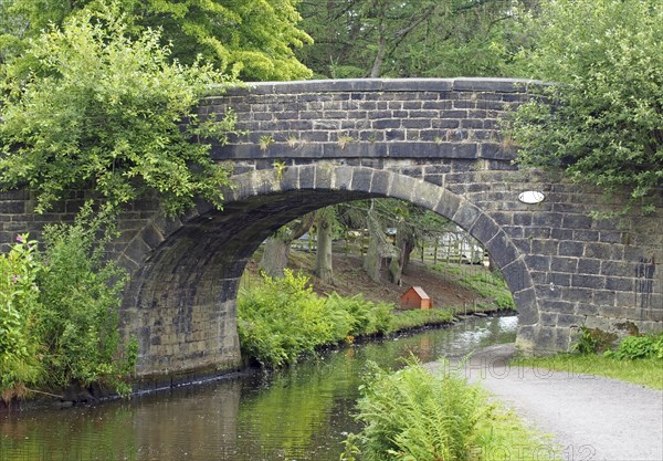 An old stone bridge crossing the rochdale canal at mytholmroyd west yorkshire with a waterside