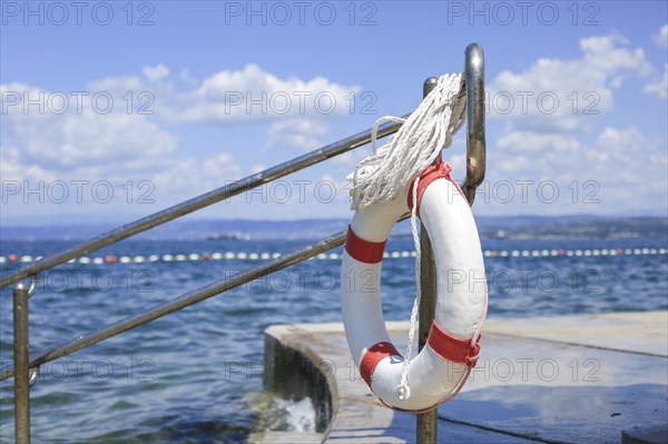 Emergency lifebuoy hanging on fence near sea at beach