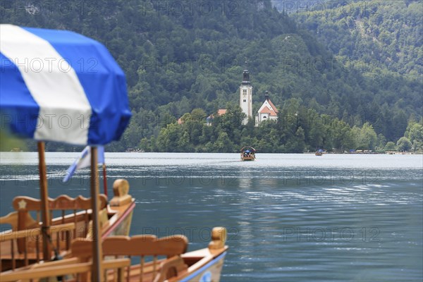 Lake Bled with traditional boat. Beautiful mountain lake in summer with small Church on island with
