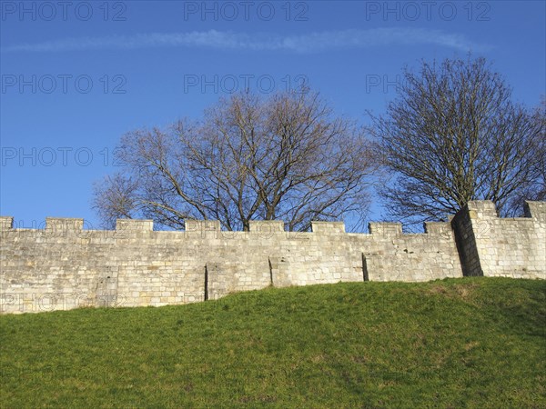 A view of the ancient medieval city walls of york with grass covered embankment and blue sky