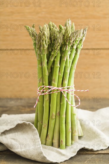 Bunch of green asparagus on wooden table with linen cloth