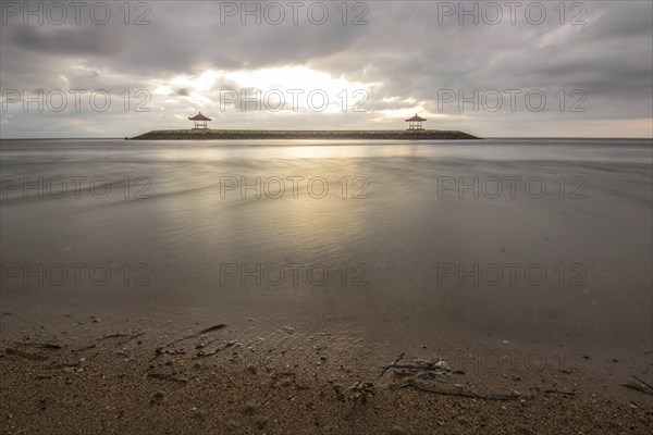 Beautiful seascape in the morning. Tropical sandy beach with breakwater and reflection of the sky