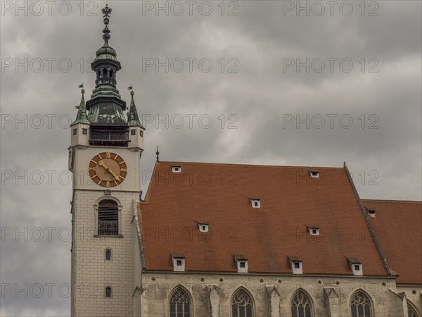 Church with a red roof and a Gothic clock tower under a cloudy sky, Dürnstein, Wachau, Danube,