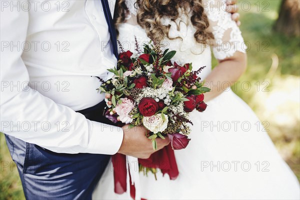 Bride and groom is holding wedding bouquet.