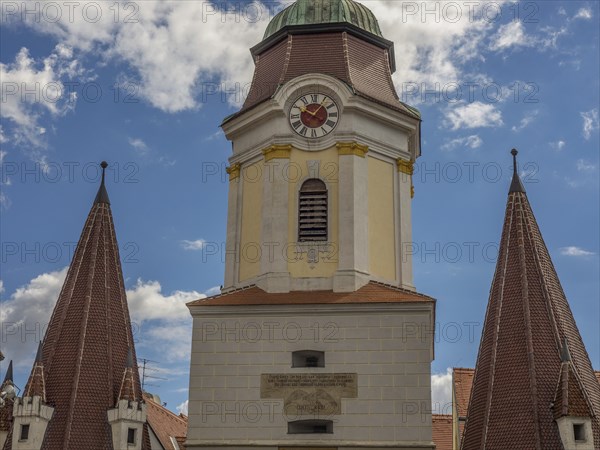 A historic clock tower and church towers against a blue sky with few clouds, Dürnstein, Wachau,
