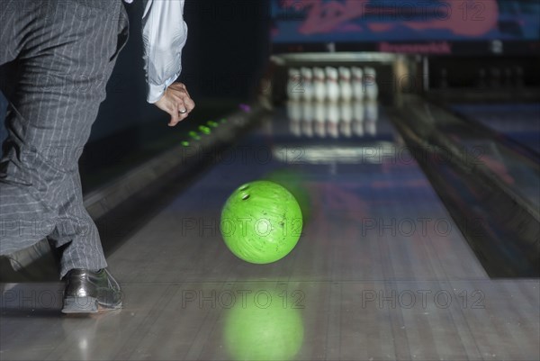 Person throwing a green bowling ball