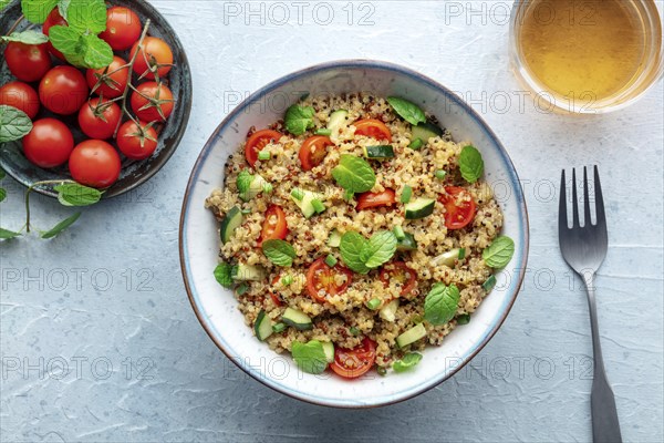 Quinoa tabbouleh salad in a bowl, a healthy dinner with tomatoes and mint, overhead flat lay shot